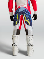 Alpinestars Jeugd Supertech Dyna broek 2027 in rood, wit en navy blauw, professionele motocrossbroek met stretchconstructie en witte motorlaarzen.