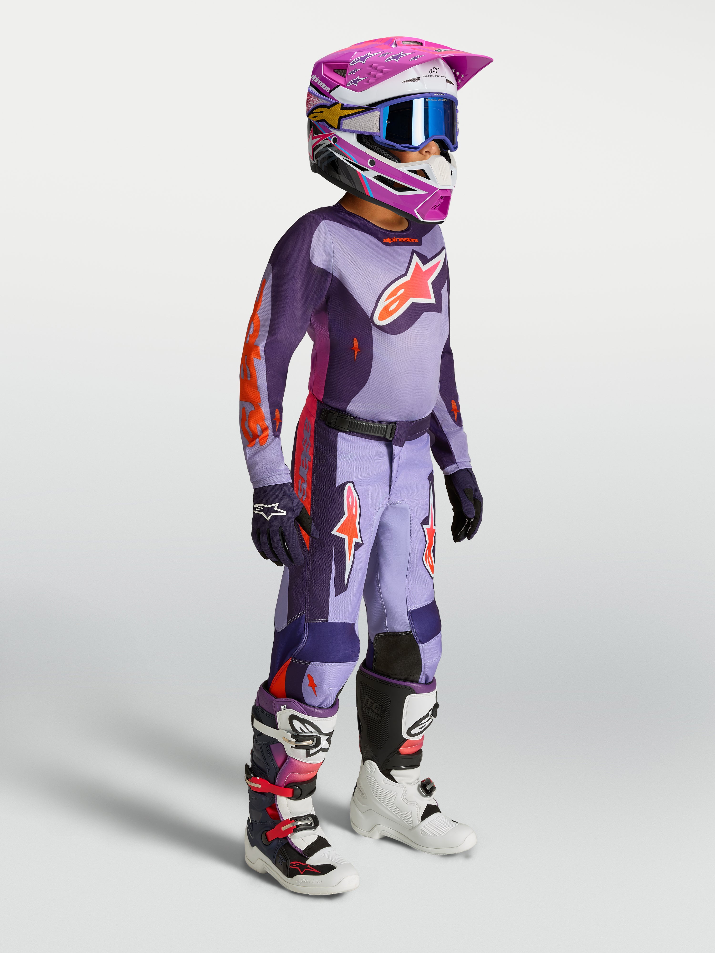 Alpinestars jeugd Fluid Hunt broek, paarse en violette motocrossbroek voor jonge rijders, met helm en motorlaarzen.