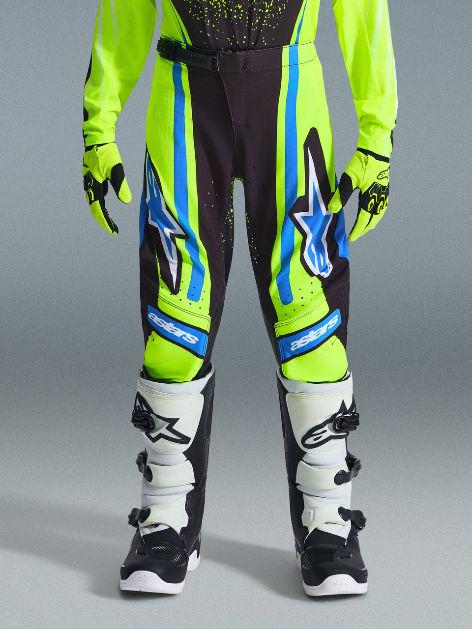 Alpinestars 2026 Jeugd Supertech Nomur Broek, motorcrossbroek, donkerblauw, fluogeel en UCLA blauw, gedragen met bijpassende handschoenen en zwart-witte laarzen, voorzien van grote sterlogo's en 'astars' branding, professionele uitrusting voor jonge rijders