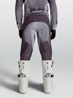 Alpinestars Jeugd Fluid Amber broek, motocrossbroek voor terreinrijden, grijs en zand, achteraanzicht met witte motorlaarzen.
