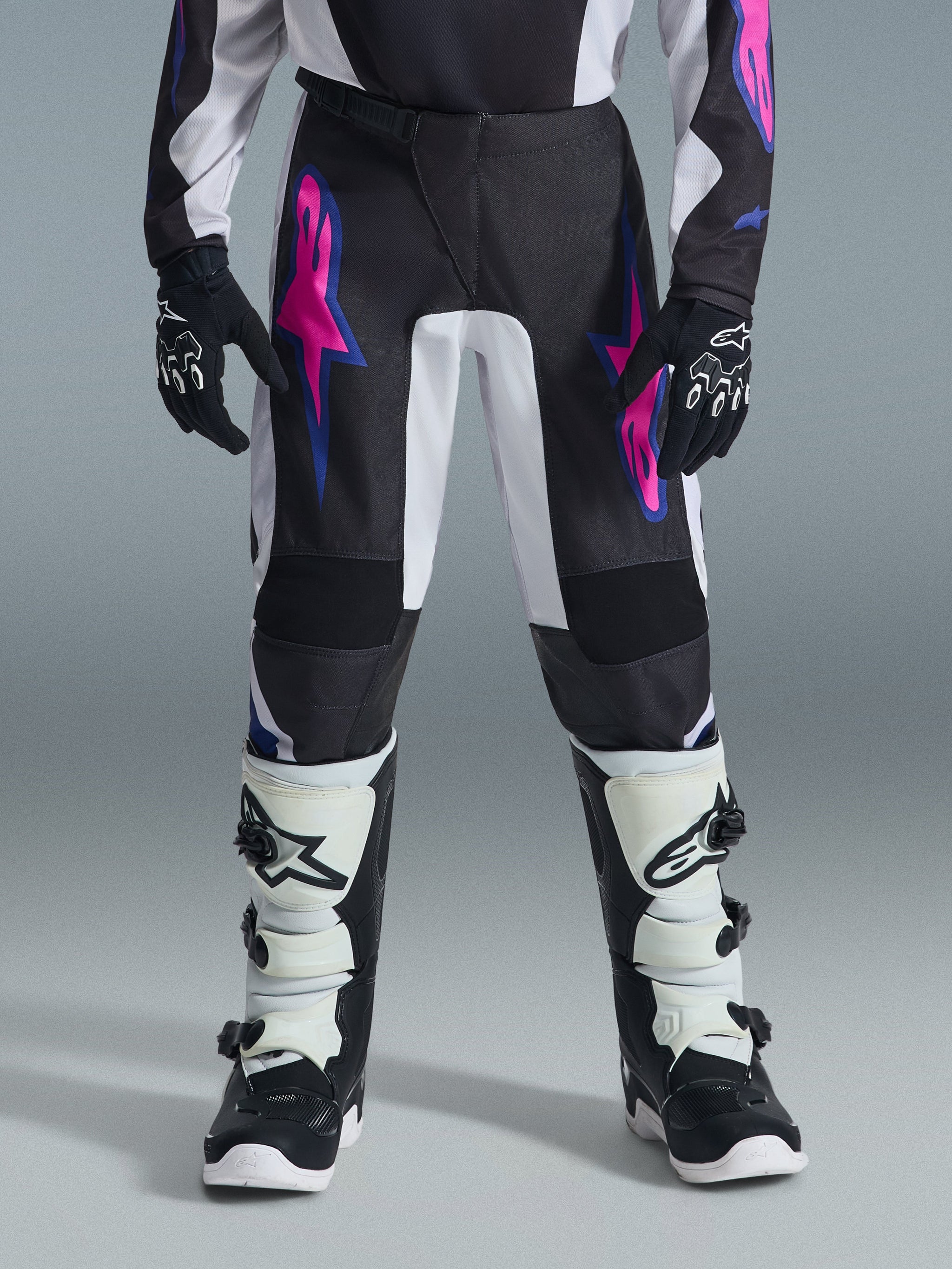 Alpinestars 2026 Youth Fluid Grid Pants, Motocross Pants, Black with pink and purple star graphics and white inner leg panels, worn with matching gear and white motocross boots, durable design for off-road racing