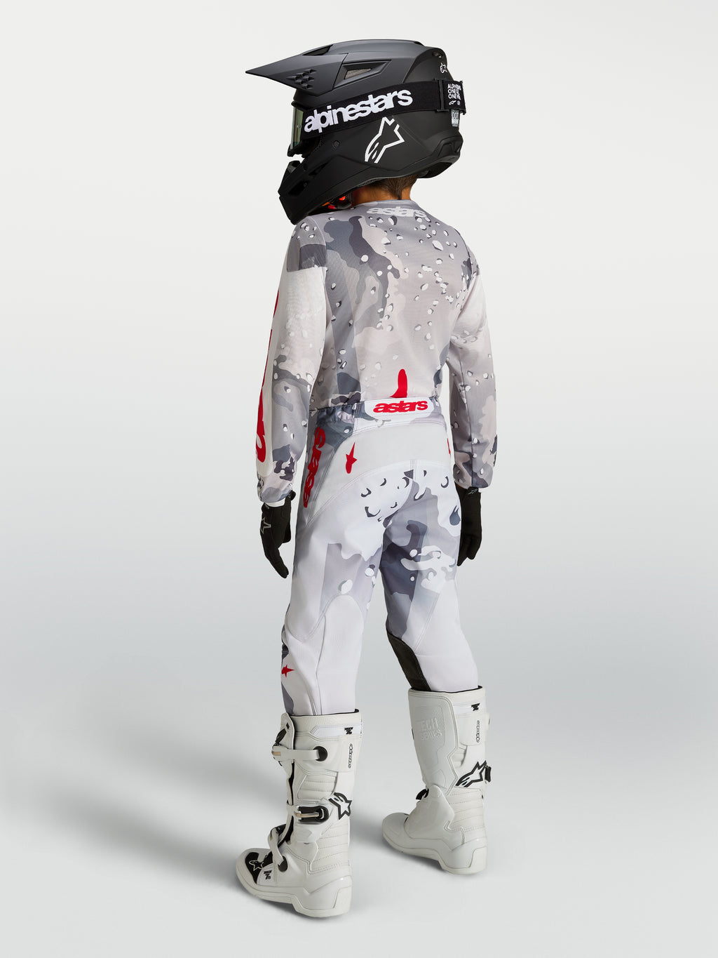Alpinestars Jeugd Fluid Lone broek, grijs camo en wit met rood, motocrossbroek op een jeugdrijder van achteren.