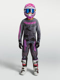 Alpinestars 2027 Jeugd Fluid Lone gear set, motorcrossuitrusting in grijs en roze camo met jersey, broek, helm en laarzen.