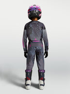 Alpinestars Jeugd Fluid Lone Gear Set, motocross-uitrusting voor kinderen, grijs en roze met technische camo graphics, achteraanzicht van model in complete outfit.