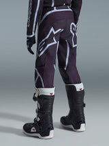 Alpinestars 2026 Youth Fluid Apex Pants, Motocross Pants, Black and Gray, worn with matching jersey and white and black boots, featuring large white A-star logos on the seat and legs, sporty design with ergonomic patterning for off-road performance.