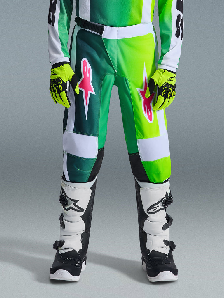 Alpinestars 2026 Youth Fluid Portl Pants, Motocross Pants, Green White and Black, featuring pink star logos on the thighs, worn with matching green jersey, neon yellow gloves, and black and white boots, coordinated gear for youth off-road racing