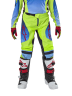Alpinestars Youth 2024 Racer Hoen broek, motorcross broek, neongeel en donkerblauw, met rode sterlogo's op de dijen, gedragen met bijpassende jersey, rood-zwarte handschoenen en witte, zwarte en rode motorcrosslaarzen, duurzame uitrusting voor off-road rijden
