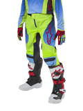 Alpinestars Youth 2024 Racer Hoen motorcrossbroek, jeugd crossbroek, neongeel en Blue Night Navy met rode accenten, gedragen met bijpassende handschoenen en witte, zwarte en rode laarzen, sportieve pasvorm en voorgevormde pijpen voor off-road racen