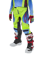 Alpinestars Youth 2024 Racer Hoen motorcrossbroek, jeugd crossbroek, neongeel en Blue Night Navy met rode accenten, gedragen met bijpassende handschoenen en witte, zwarte en rode laarzen, sportieve pasvorm en voorgevormde pijpen voor off-road racen