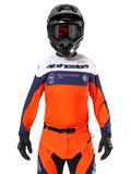 Alpinestars Pro-Dura Jersey, motorcross shirt, marineblauw, fel oranje en wit, gedragen met een zwarte helm en handschoenen, voorzien van lasergeperforeerde ventilatiezones, opvallende branding en 'ONE GOAL. ONE VISION.' graphic op de borst
