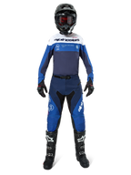 Motorcrosser in volledige race-uitrusting, Pro-Dura Jersey in Navy, Bright Blue en White, bijpassende blauwe en navy broek, zwarte helm met rode bril, zwart-witte laarzen, gecoördineerde outfit voor enduro en off-road rijden