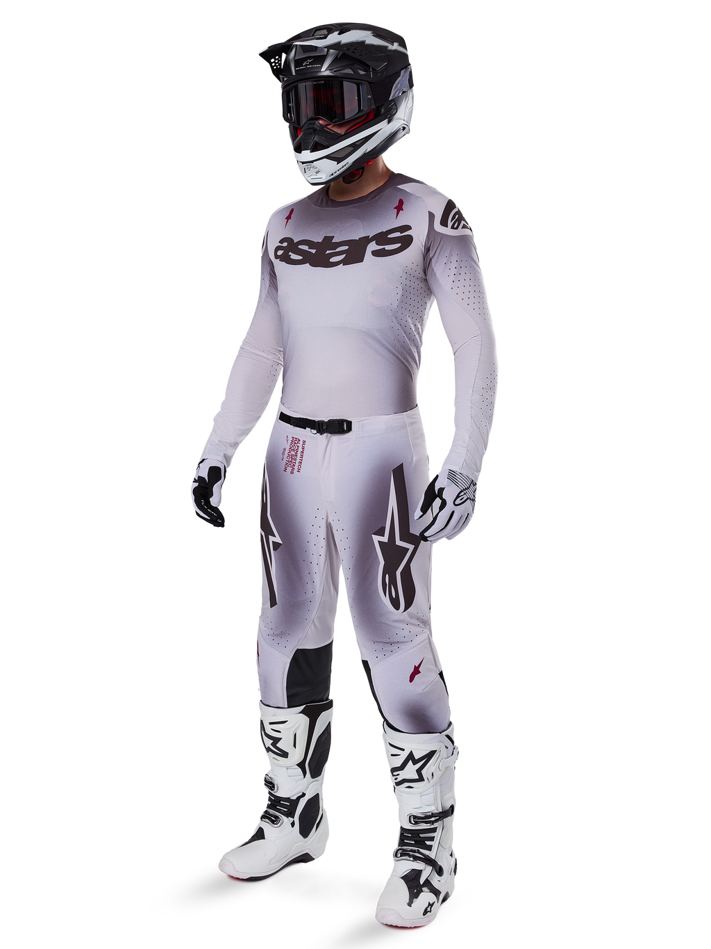 Motorcrosser in de 2025 Supertech Maker broek in Silver Black, gecombineerd met een bijpassende zilveren en grijze jersey, zwart-witte helm en witte racelaarzen, met een technische atletische pasvorm voor professionele off-road prestaties.