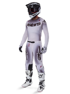Motorcrosser in de 2025 Supertech Maker broek in Silver Black, gecombineerd met een bijpassende zilveren en grijze jersey, zwart-witte helm en witte racelaarzen, met een technische atletische pasvorm voor professionele off-road prestaties.