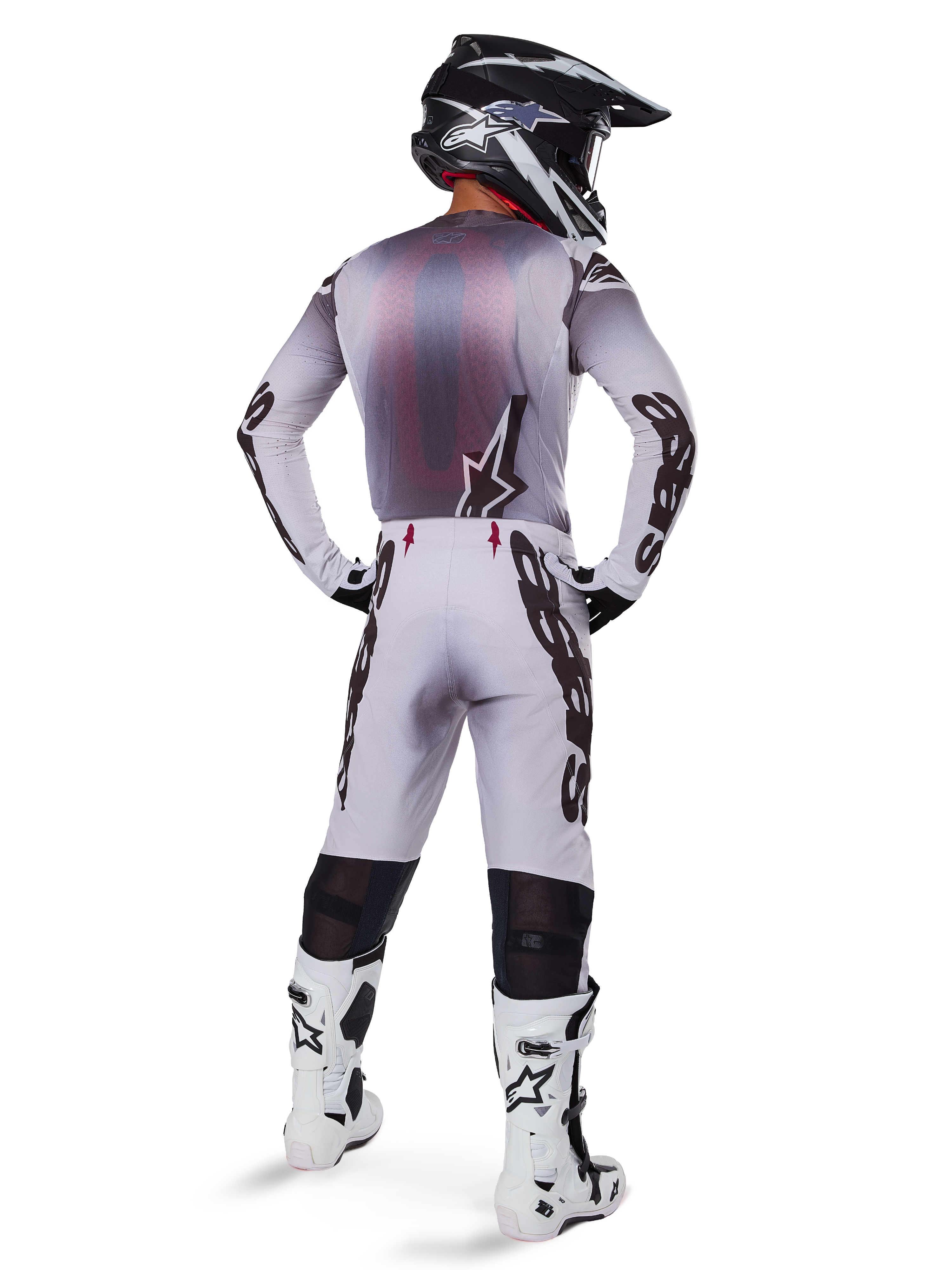 Motorcrossrijder van achteren gezien in de 2025 Supertech Maker Gear Set in het wit, voorzien van een grijs en witte jersey met zwarte Alpinestars-branding, bijpassende motorcrossbroek, wit-zwarte laarzen en een zwarte helm, gecoördineerde off-road race-uitrusting