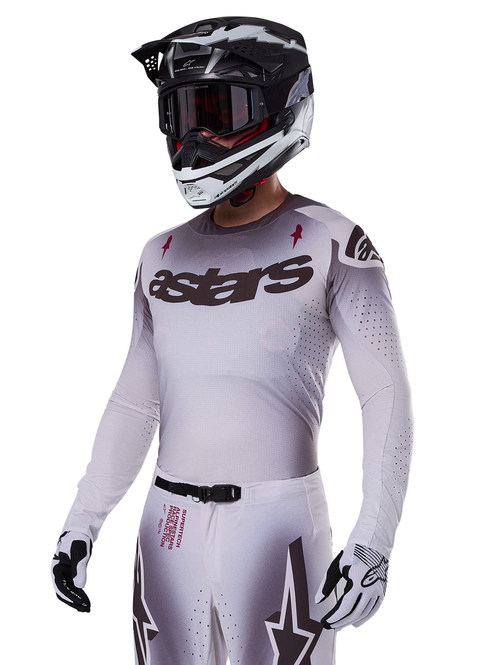 Alpinestars 2025 Supertech Maker Jersey, motorcross raceshirt, zilver en zwart kleurverloop, ademend stretch-mesh met lasergesneden perforaties, gedragen met bijpassende broek en helm, voorzien van 'astars' branding, complete professionele off-road uitrusting