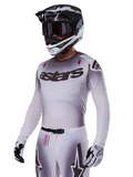 Alpinestars 2025 Supertech Maker Jersey, motorcross raceshirt, zilver en zwart kleurverloop, ademend stretch-mesh met lasergesneden perforaties, gedragen met bijpassende broek en helm, voorzien van 'astars' branding, complete professionele off-road uitrusting