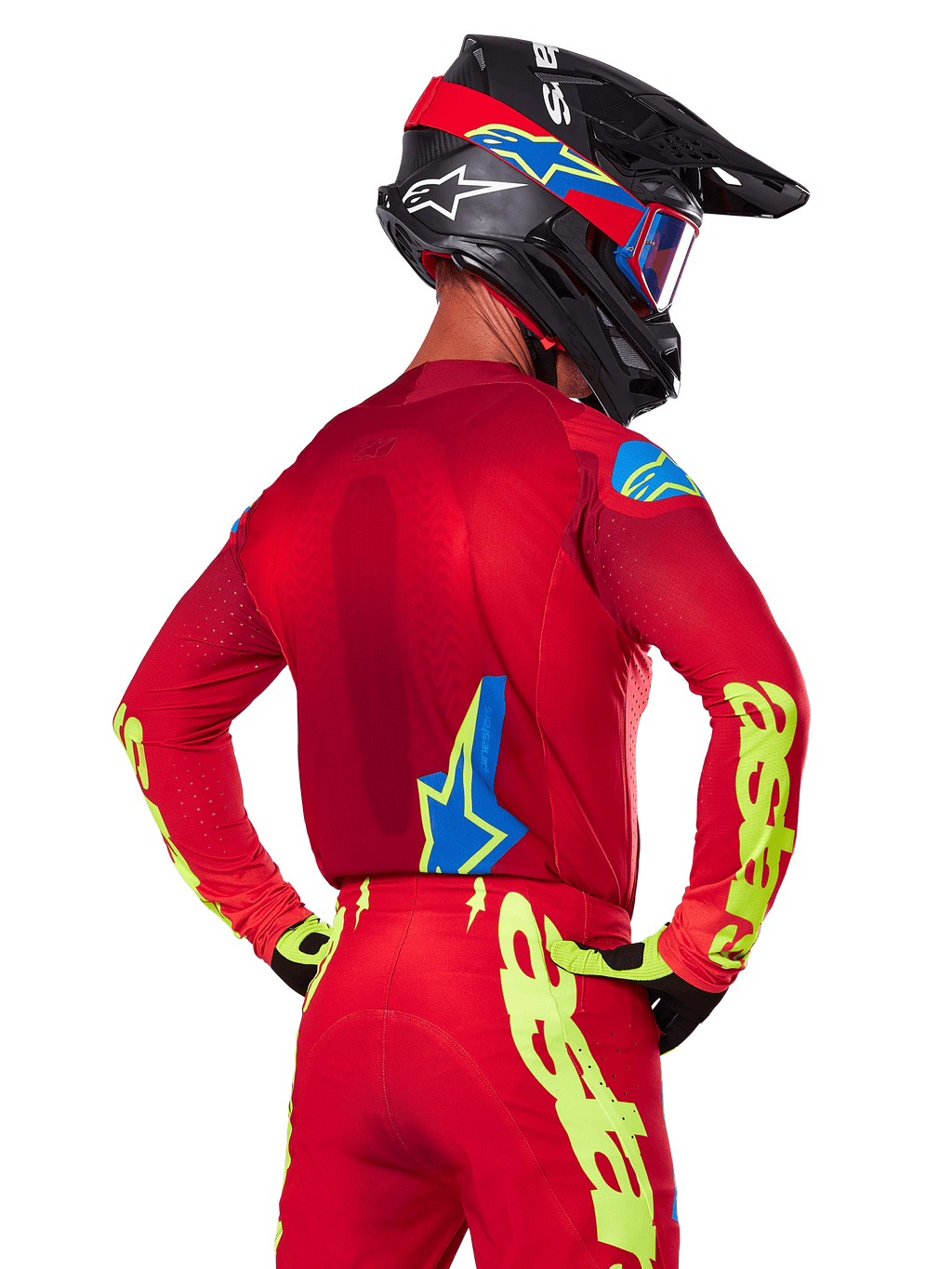 Achteraanzicht van een motocrossrijder die de Alpinestars 2025 Supertech Maker Gear Set in het rood draagt, bestaande uit een rode jersey met neongele branding op de mouwen, een bijpassende rode broek, een zwarte helm met blauwe en rode accenten en bijpassende zwart-gele handschoenen.