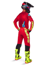 Motocross rider seen from the back wearing the Alpinestars 2025 Supertech Maker Jersey, Bright Red and Yellow Fluo, matching pants with yellow branding, yellow fluo boots, and a black and red helmet, coordinated outfit for pro-level off-road racing