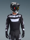 Alpinestars 2026 Racer Air Riway Jersey, zwart-wit motorcross jersey met 'astars' branding, gedragen door een rijder met bijpassende zwarte helm, crossbril en broek, voorzien van ademende mesh-panelen voor off-road racen.