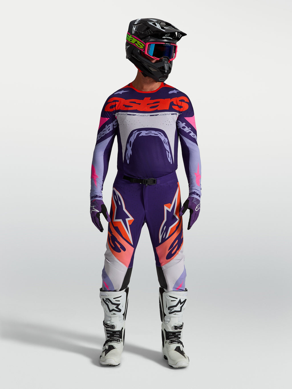 Alpinestars Supertech Dyna jersey, heren-motocrossjersey in lichtpaars en dieppaars met fluo roze accenten, gedragen met een bijpassende broek en witte motorlaarzen.