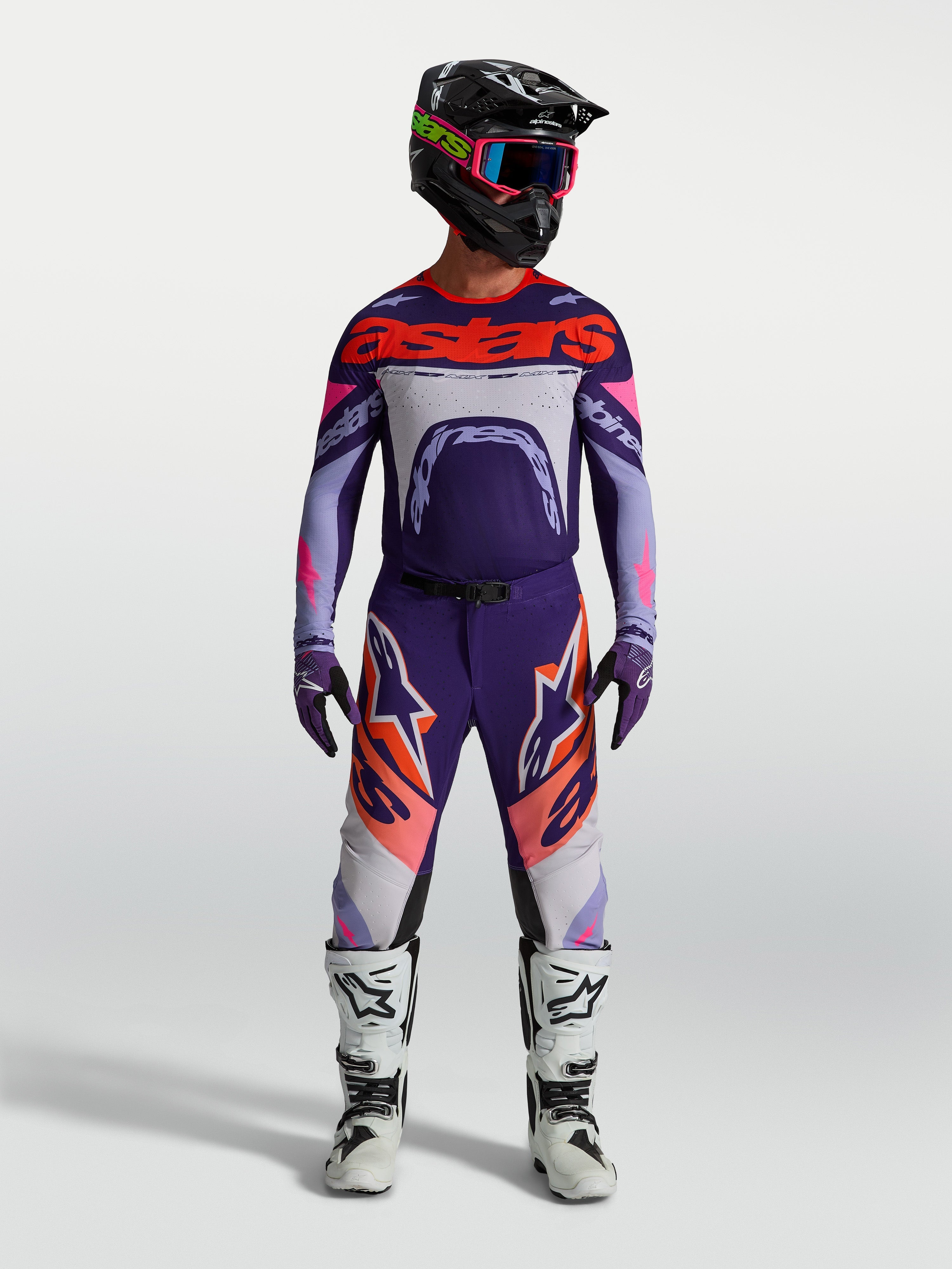 Alpinestars Supertech Dyna jersey, heren-motocrossjersey in lichtpaars en dieppaars met fluo roze accenten, gedragen met een bijpassende broek en witte motorlaarzen.