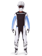 Motorcrosser in volledige Alpinestars 2025 Techstar Melt-uitrusting, zwart jersey met lichtblauwe gradient mouwen, witte broek met zwarte en blauwe accenten, witte helm met zwarte crossbril, witte en zwarte laarzen en handschoenen, gecoördineerde MX-gearset voor off-road racen