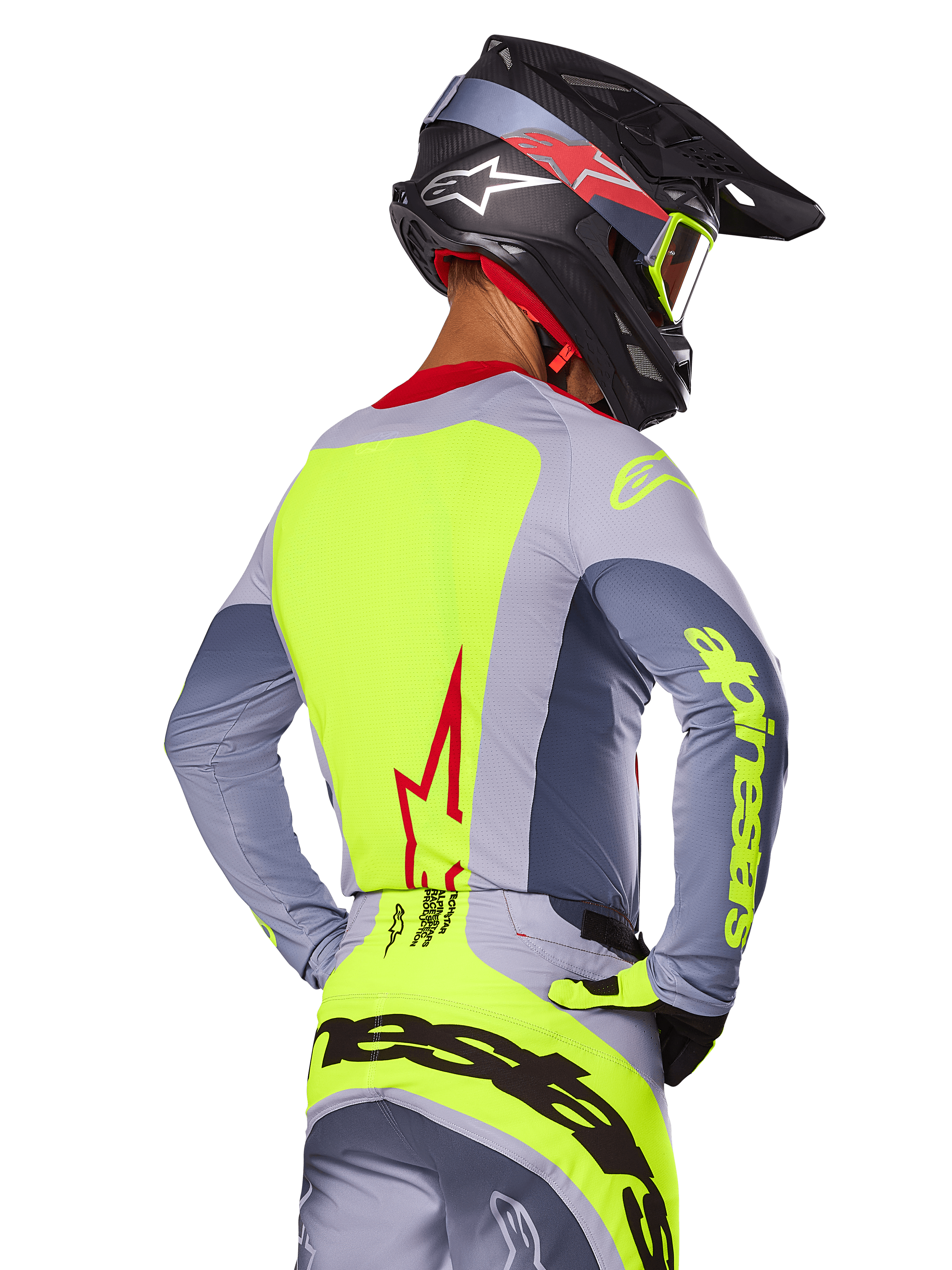 Alpinestars 2025 Techstar Melt Jersey, Bright Red Gray, achteraanzicht van motorcrossrijder in grijze en neongele race-uitrusting, rood sterlogo op de rug, bijpassende zwarte en rode helm, hoogwaardige off-road kleding