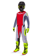Alpinestars 2025 Techstar Melt Jersey, motorcrossrijder in helderrood en grijs, rode borst en grijze mouwen met fluorescerend gele accenten, bijpassende broek, felgele laarzen en handschoenen, zwarte helm met bril met geel montuur, complete off-road race-uitrusting