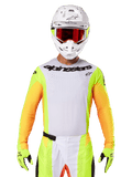 Alpinestars 2025 Techstar Melt Jersey, motorcross racekleding, wit borststuk met neongele en oranje mouwen, rijder draagt witte helm en rode bril, neongele handschoenen met zwarte logo's, levendige kleurstelling voor off-road prestaties