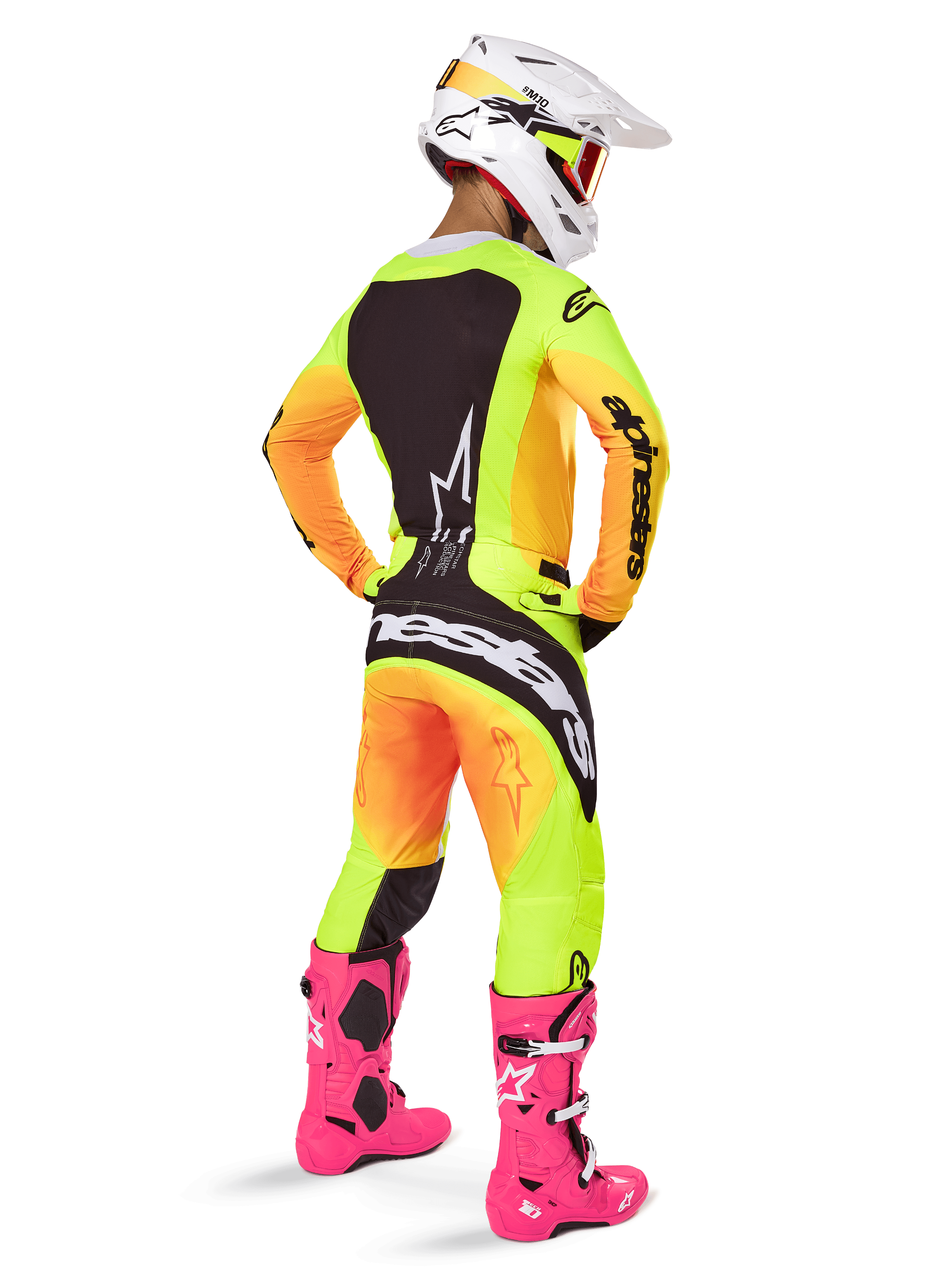 Motorcrosser van achteren die de Alpinestars 2025 Techstar Melt Jersey draagt, opvallend geel en oranje kleurverloop met zwarte delen, bijpassende motorcrossbroek, felroze laarzen en witte helm, atletische pasvorm voor off-road competitie.