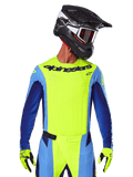 Alpinestars 2025 Techstar Melt Jersey, motorcross racetenue, fluogeel en blauw, voorzien van laser-gesneden ventilatie en een atletische racepasvorm, gedragen door een rijder met een zwarte helm en fluogele handschoenen