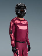 Alpinestars 2026 Racer Riway Gear Set, motocrossrijder met bordeauxrode en roze jersey met opvallende 'astars' branding, bijpassende broek met roze accenten, zwarte helm en handschoenen, professionele race-outfit voor off-road motorcross