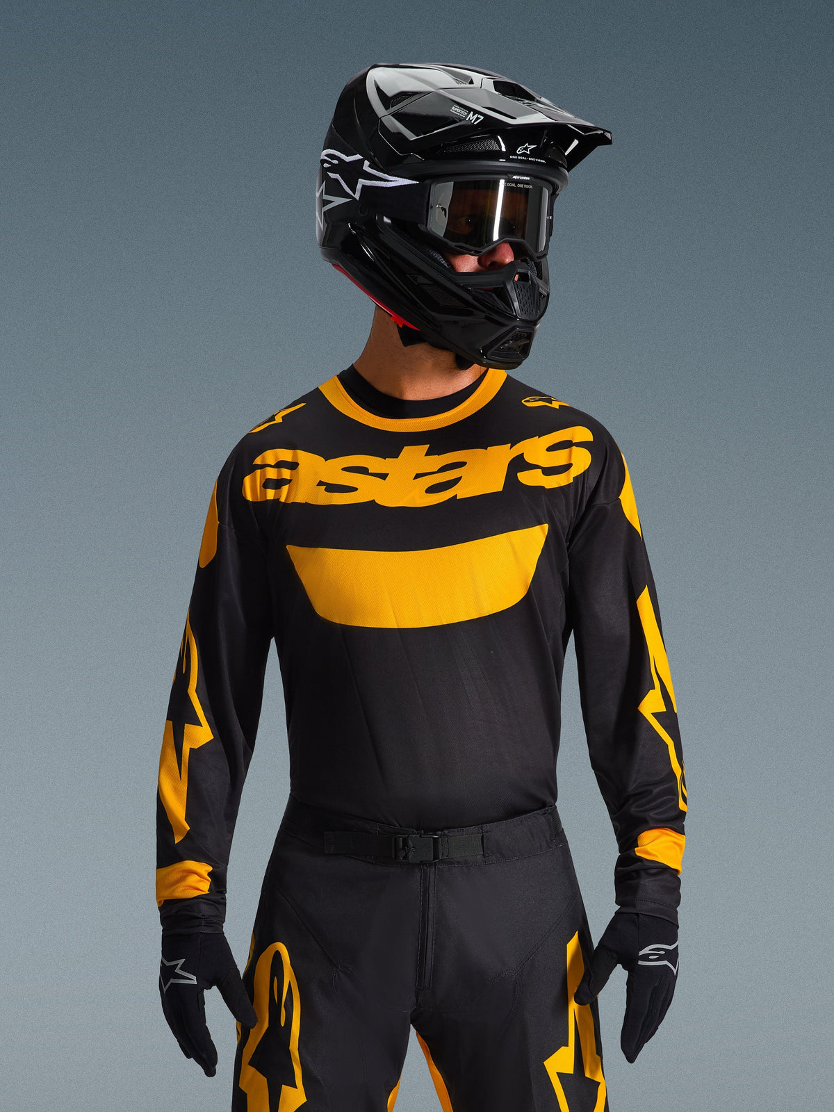 Motorcrossrijder in de Alpinestars 2026 Racer Riway Jersey in geel en zwart, voorzien van een opvallend geel 'astars' logo op de borst, gecombineerd met een bijpassende zwart-gele broek, een zwarte helm met crossbril en zwarte handschoenen, professionele off-road race-uitrusting.