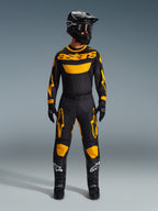 Motorcrosser draagt de 2026 Racer Riway Jersey in geel en zwart, gecombineerd met bijpassende broek, zwarte helm en zwarte laarzen met witte Alpinestars-logo's, volledige uitrusting voor off-road racing.