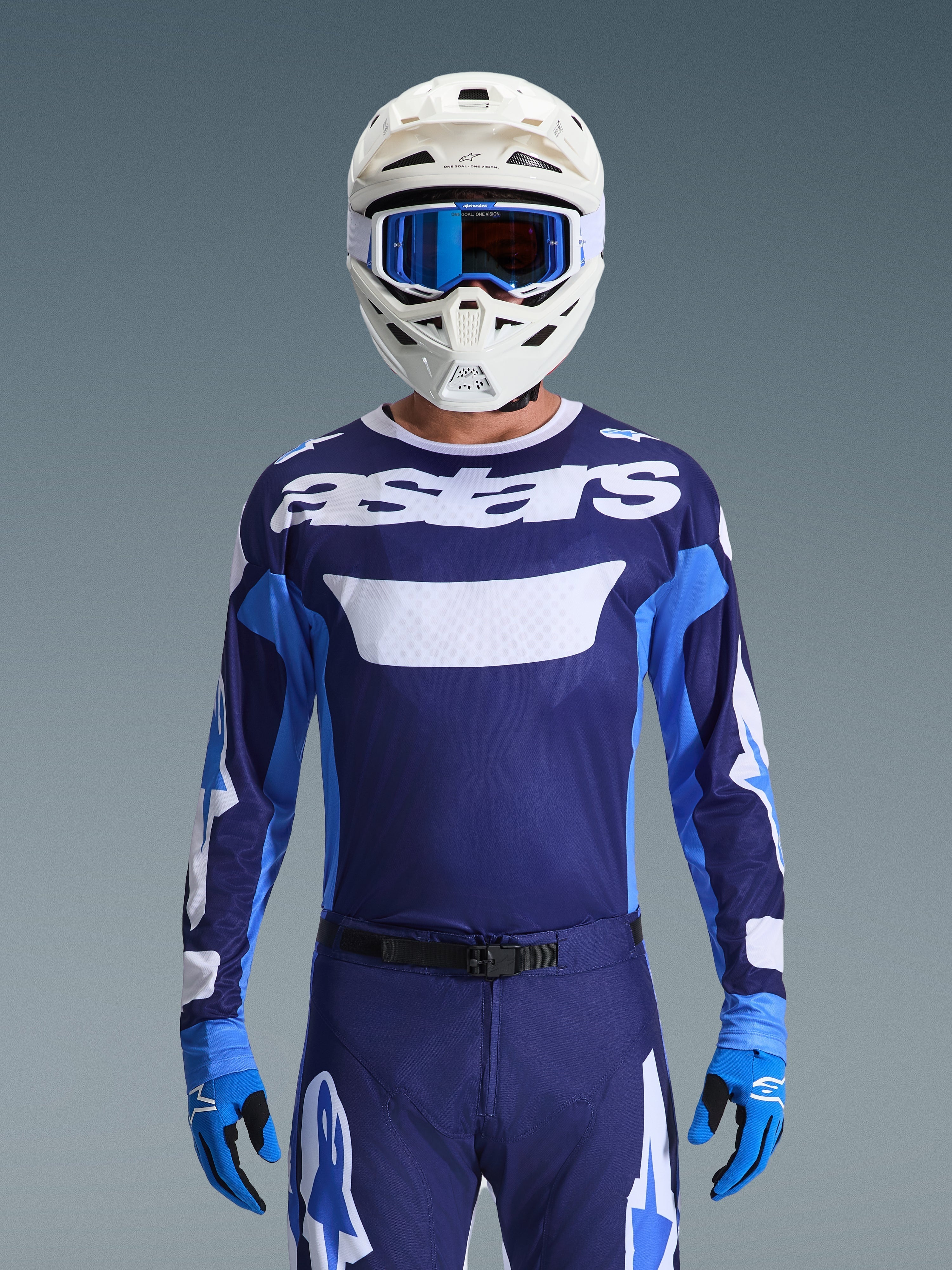 Motocrossrijder in Alpinestars 2026 Racer Riway Jersey, UCLA Blue en wit met wit 'astars'-logo op de borst, witte helm met blauwe bril, bijpassende motorcrossbroek en blauwe handschoenen, gecoördineerde off-road race-uitrusting