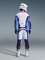 Rear view of a motocross rider wearing the Alpinestars 2026 Racer Riway Jersey and Pants in Ucla Blue and White, coordinated with a white helmet, black gloves, and white motocross boots, high-performance gear for off-road racing