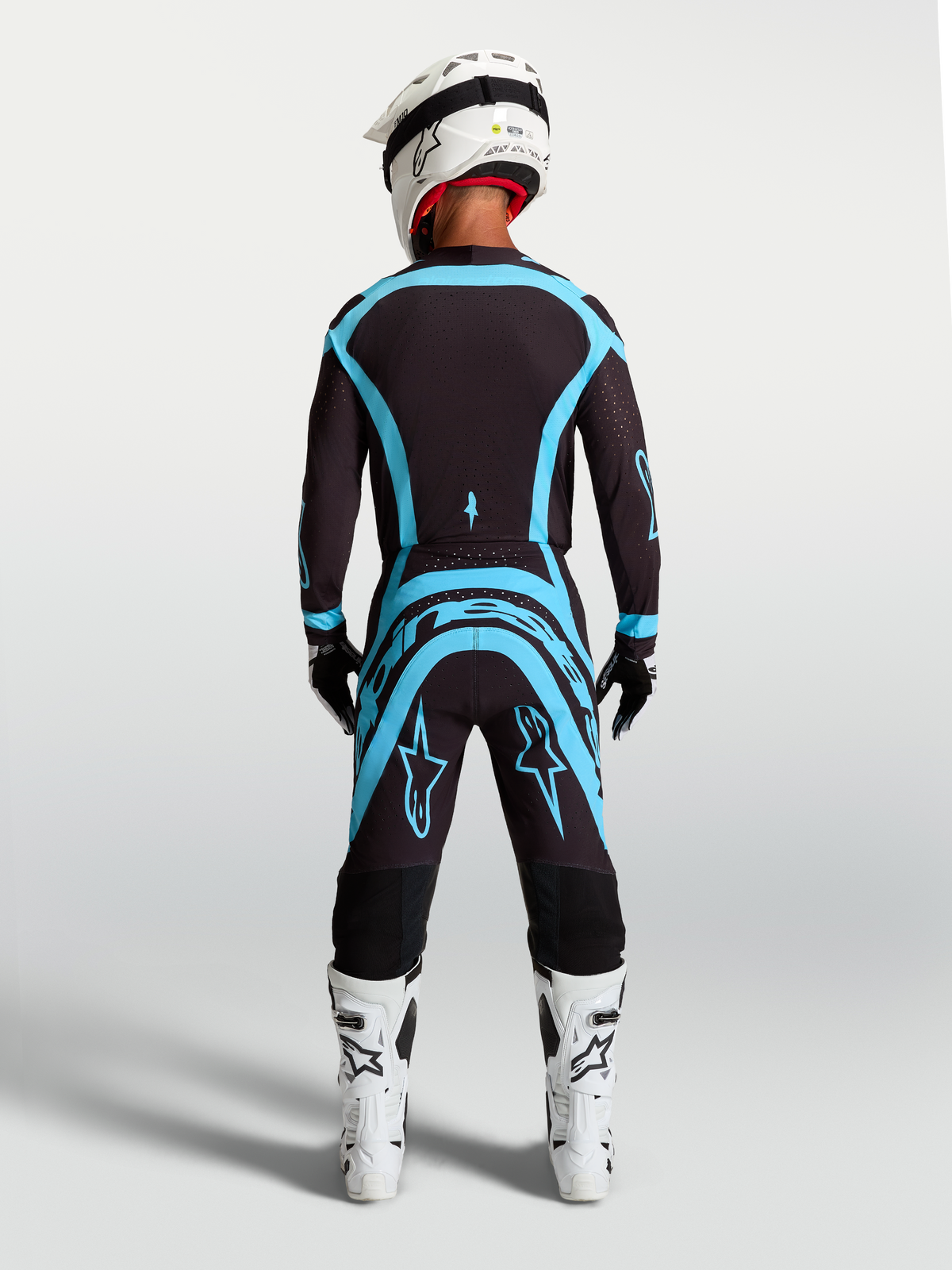 Alpinestars Supertech Vesta uitrustingsset voor motorcross, jersey en broek in zwart en turquoise, achteraanzicht, atletische racepasvorm.