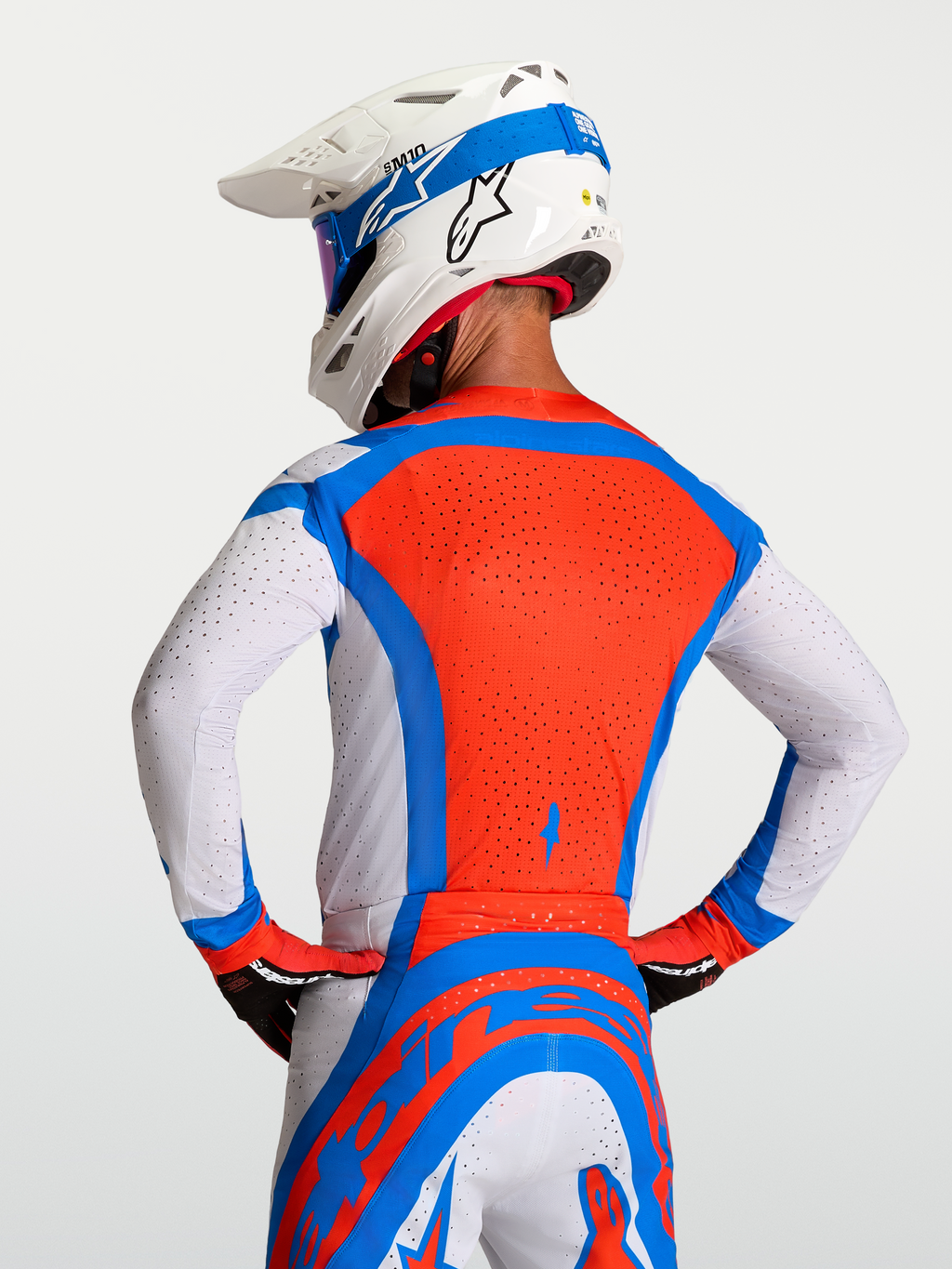 Alpinestars Supertech Vesta Jersey, heren-motocrossjersey in rood, blauw en wit met ademende laser-gesneden perforaties, achteraanzicht van een rijder.