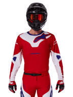 Alpinestars 2025 Racer Veil Jersey, motocross raceshirt, rood, wit en blauw, lange mouwen, gedragen met zwarte helm en oranje bril, bijpassende rode handschoenen en broek, gestroomlijnd ontwerp voor off-road prestaties