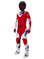 Alpinestars 2025 Racer Veil Gear Set, motorcross-racekleding, helderrood en wit met blauwe logo-accenten, gedragen met een zwarte helm, rode handschoenen en witte laarzen, volledige beschermende uitrusting voor off-road prestaties