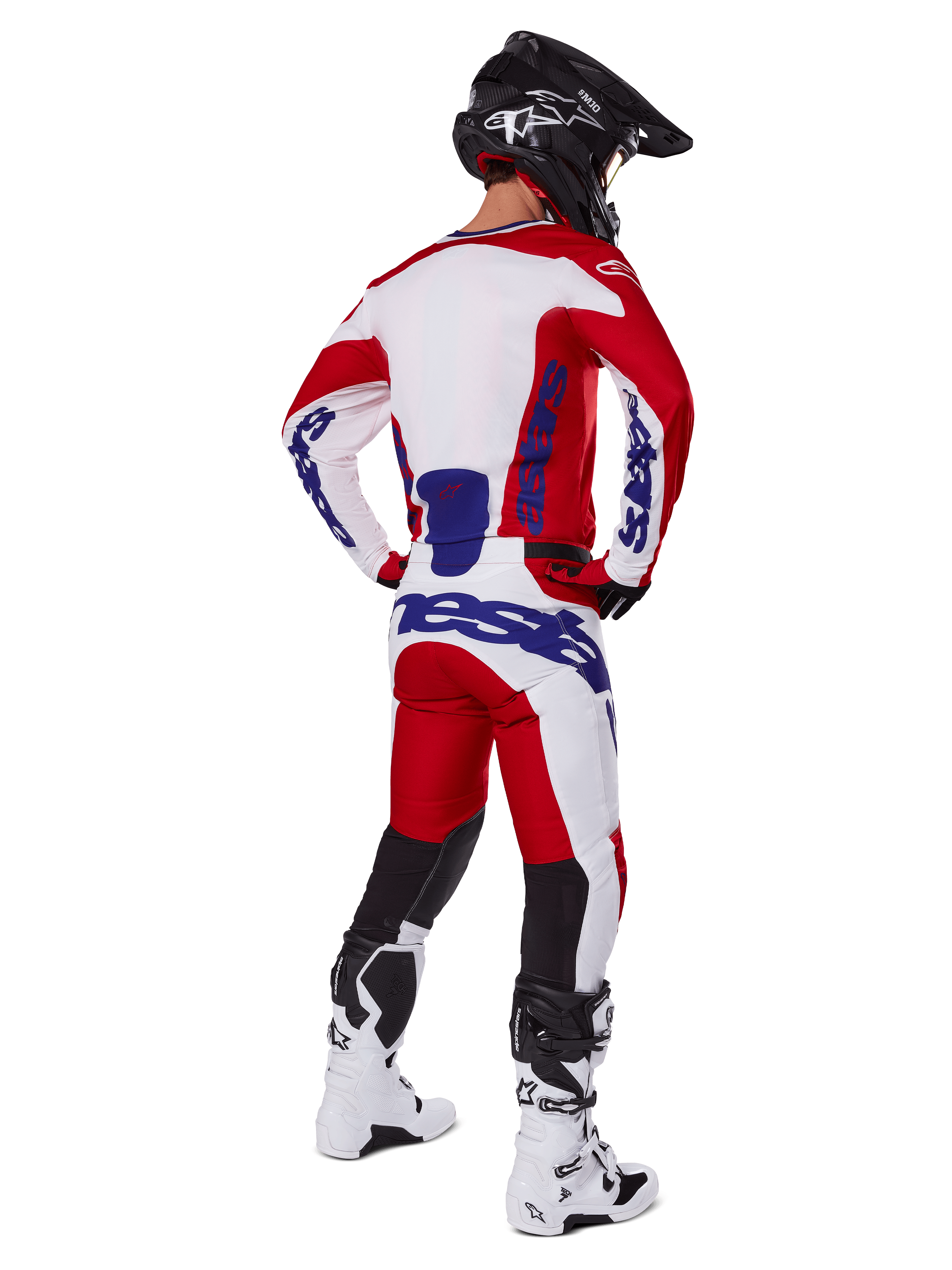 Alpinestars 2025 Racer Veil Jersey en broek, motorcross outfit van achteren gezien, rood en wit met blauwe merkdetails, zwarte helm en witte laarzen, complete kledingset voor off-road racen