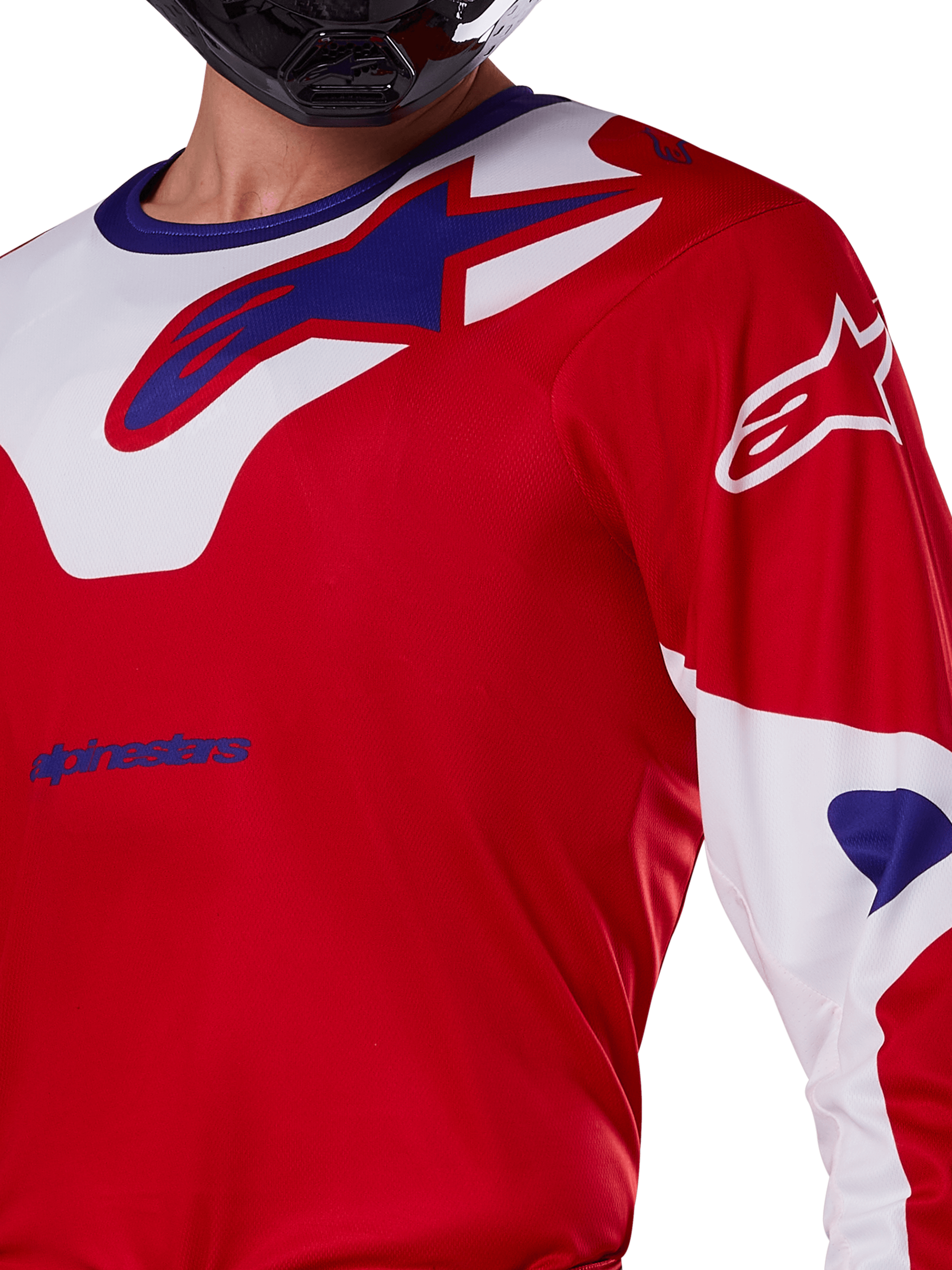 Alpinestars 2025 Racer Veil Jersey, motocross shirt, felrood en wit, close-up van het bovenlichaam en de borst, blauw Alpinestars-logo op een wit kraagpaneel, rode mouwen met witte accenten, gedragen met een zwarte helm, technische off-road kleding