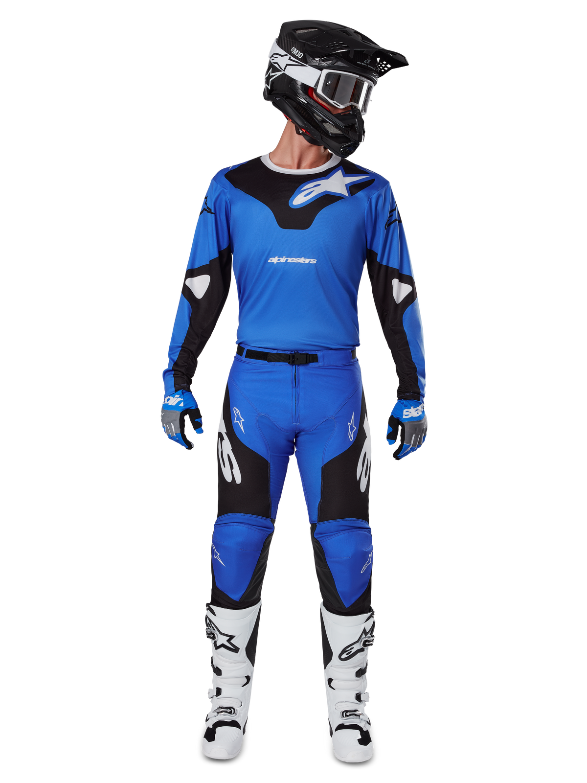Motocrossrijder die de Alpinestars 2025 Racer Veil Gear Set draagt, blauw-zwarte jersey met bijpassende broek, zwarte helm met witte crossbril, witte en zwarte laarzen, gecoördineerde race-outfit voor off-road motorcross.