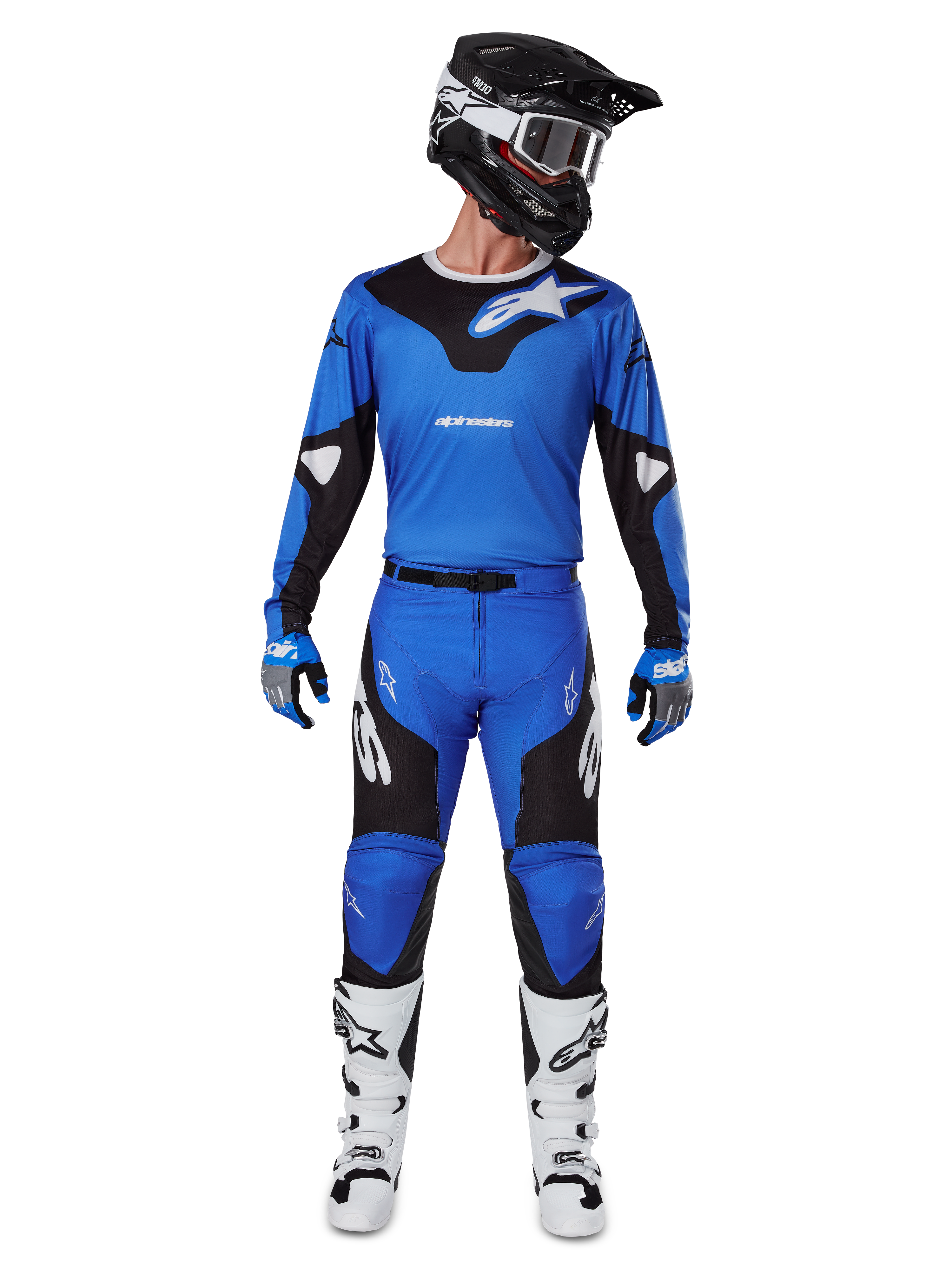 Motocrossrijder die de Alpinestars 2025 Racer Veil Gear Set draagt, blauw-zwarte jersey met bijpassende broek, zwarte helm met witte crossbril, witte en zwarte laarzen, gecoördineerde race-outfit voor off-road motorcross.