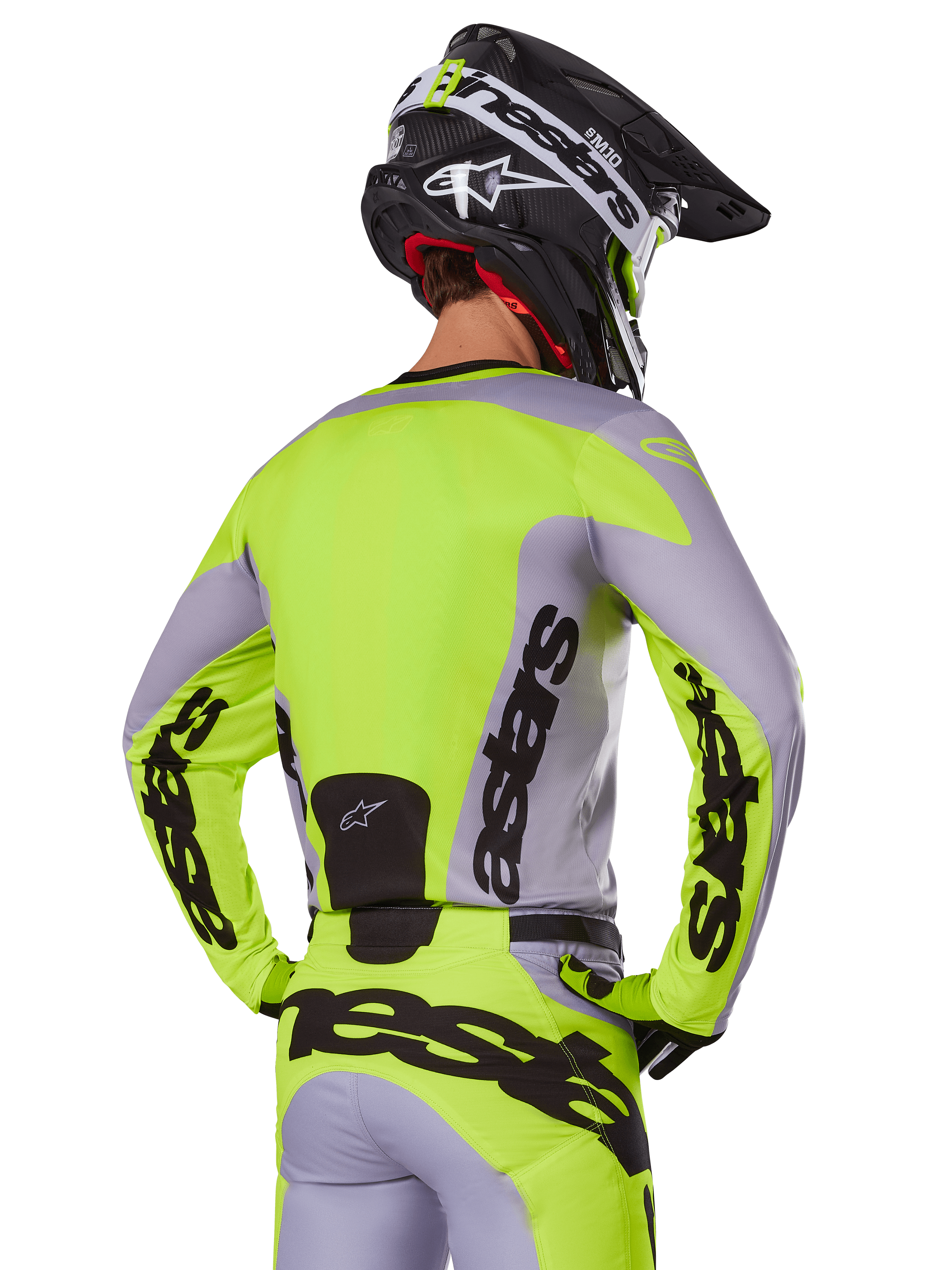 Alpinestars 2025 Racer Veil Jersey in Gray Yellow Fluo, motocross jersey van achteren gezien, met opvallende 'astars' branding op de rug en mouwen, gecombineerd met bijpassende broek en zwarte helm voor een complete race-look.
