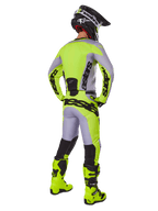 Motocrossrijder van achteren in Alpinestars 2025 Racer Veil Gear Set, grijs en fluorgeel jersey en broek, bijpassende fluorgele laarzen en zwart-gele helm, gecoördineerde outfit voor off-road racing