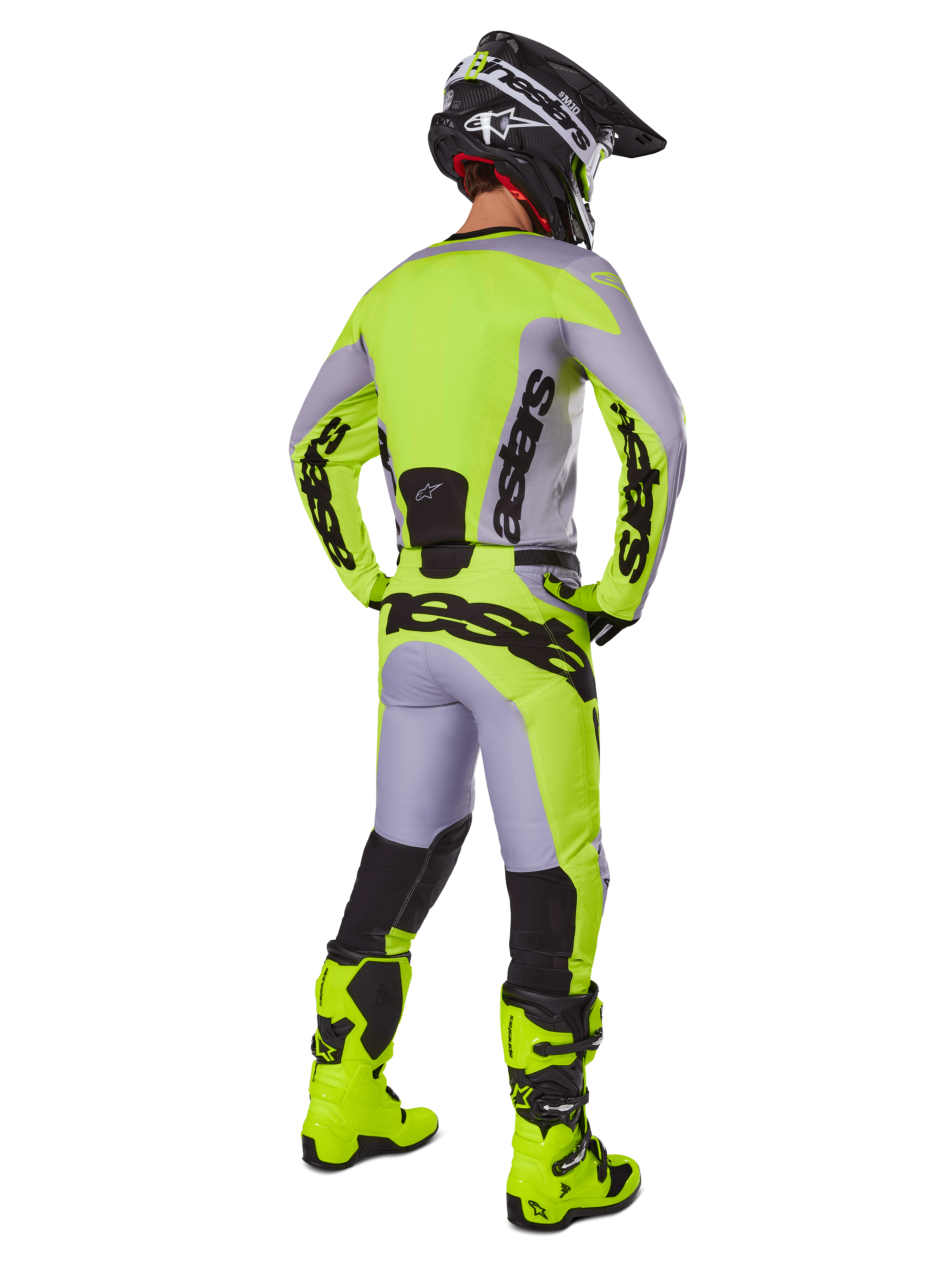 Motocrossrijder van achteren in Alpinestars 2025 Racer Veil Gear Set, grijs en fluorgeel jersey en broek, bijpassende fluorgele laarzen en zwart-gele helm, gecoördineerde outfit voor off-road racing