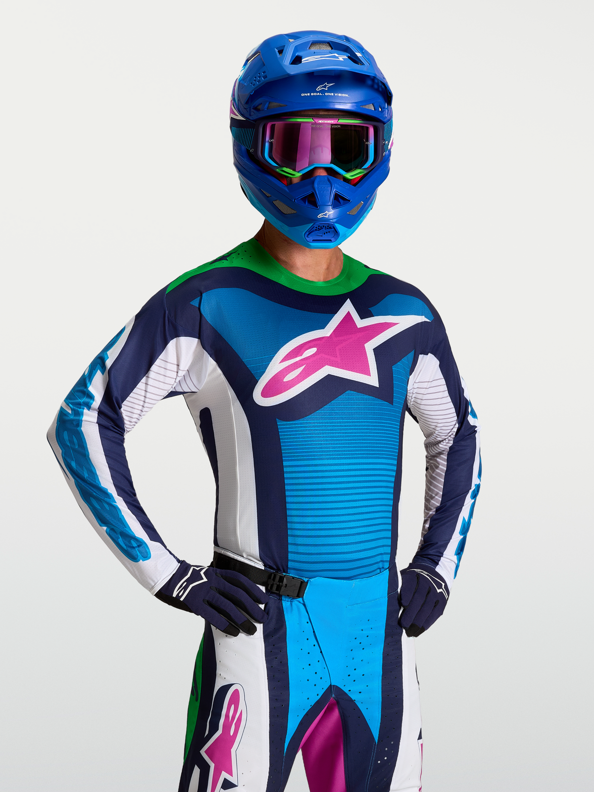 Alpinestars Techstar Maven Jersey, heren-motorcrossjersey in blauw en wit met een roze sterlogo en fluogroene kraag, gedragen door een rijder in volledige off-road race-uitrusting.