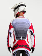 Alpinestars Techstar Maven Jersey, rood en wit ademend motorcrossjersey, achteraanzicht op de rijder.