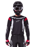 Alpinestars Fluid Haul jersey en kledingset 2025, heren motocrossoutfit, zwart en wit met rode accenten, professionele off-road racekleding inclusief helm en handschoenen.